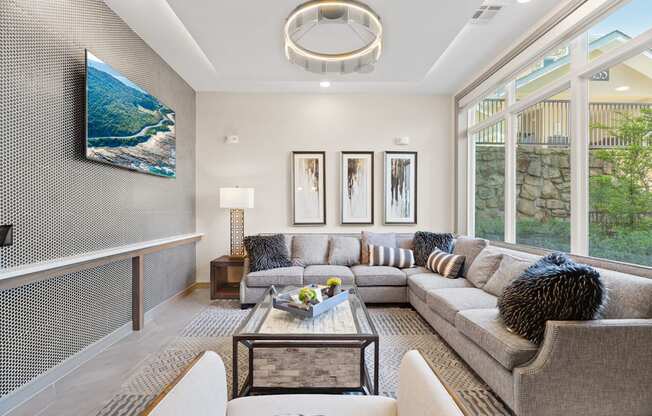 A modern living room with a grey couch, a coffee table, and a large painting on the wall.