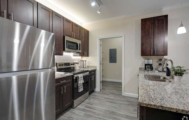 A kitchen with a stainless steel refrigerator and dark wood cabinets.