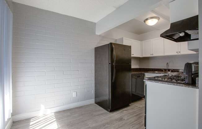 a kitchen with white cabinets and a black refrigerator