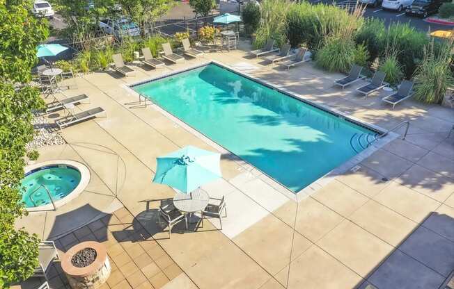 a swimming pool and patio with chairs and umbrellas