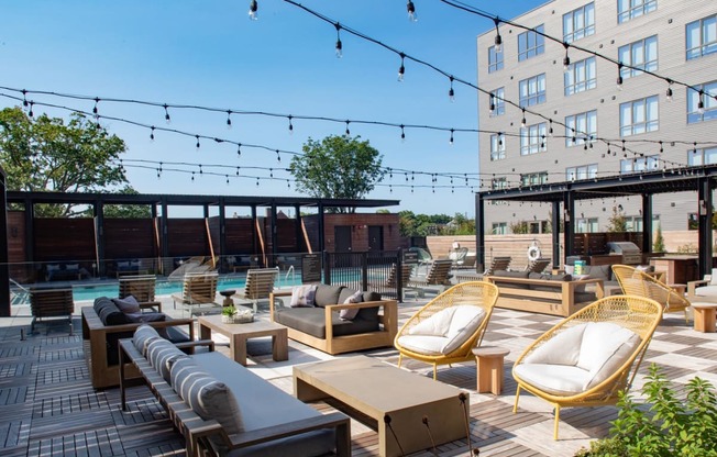a rooftop lounge area with chairs and tables and a pool