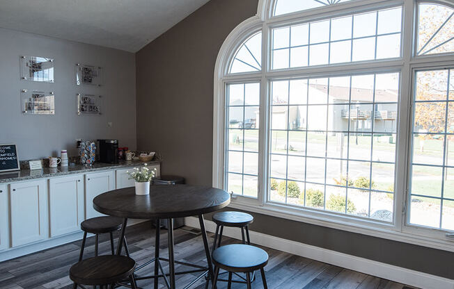 an empty room with tables and chairs and large windows