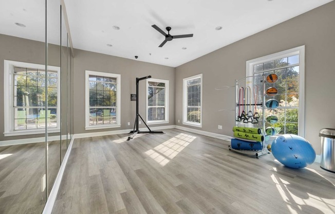 a workout room with mirrors and a ceiling fan