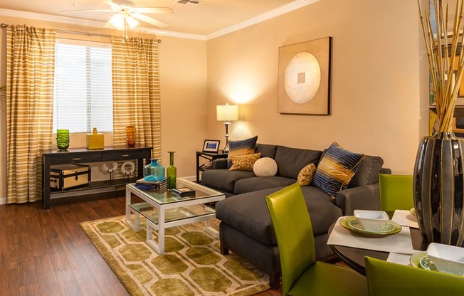 a living room with a brown couch and green chairs