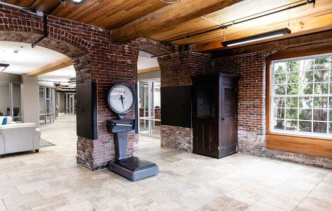 A brick column with a clock on it stands in a room with a wooden ceiling.