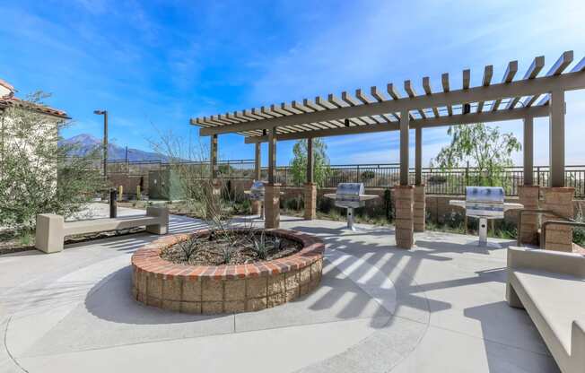 a patio with a fire pit and benches and a pergola