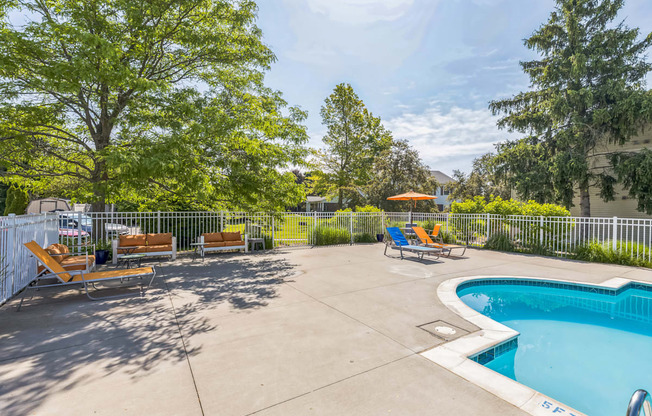 A pool area with a small pool and sun loungers.