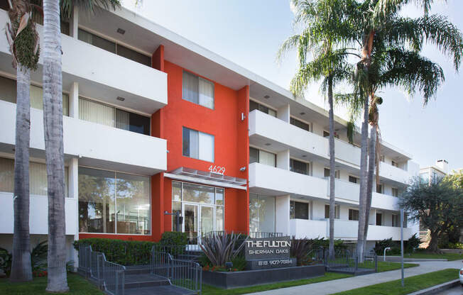 an orange and white building with palm trees in front of it