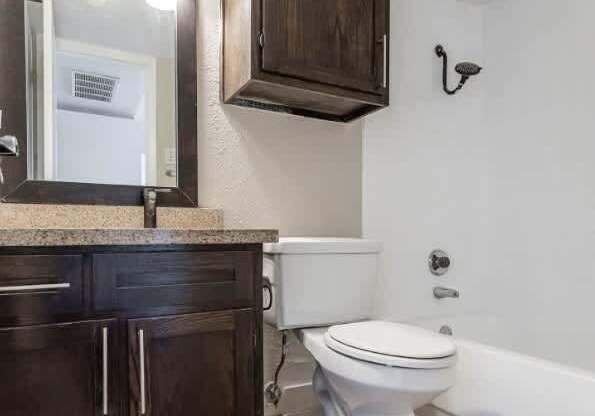 A white toilet sits in a bathroom with a wooden cabinet and a mirror above it.