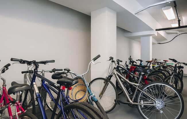 A group of bicycles are parked in a white room.