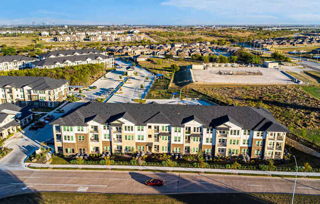 A large apartment complex with a parking lot in front.