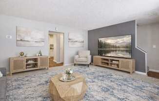 A living room with a blue carpet and a painting on the wall.