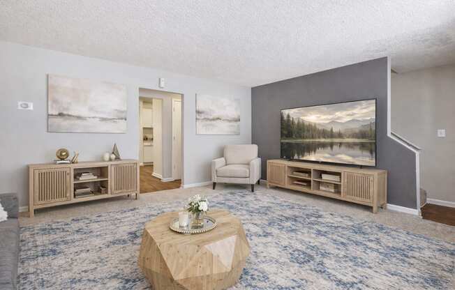 A living room with a blue carpet and a painting on the wall.