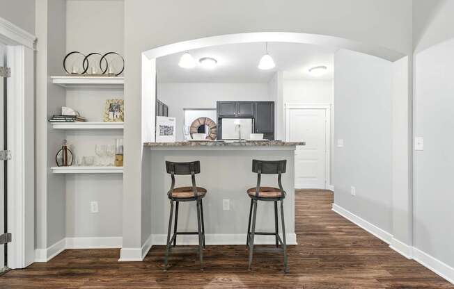 A kitchen with a bar area and two stools.