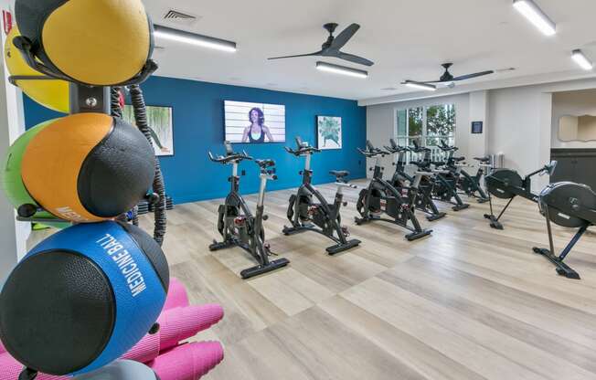 a fitness room with exercise bikes and a tv on the wall