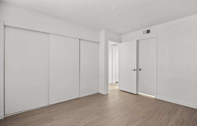 an empty room with white walls and wood floors