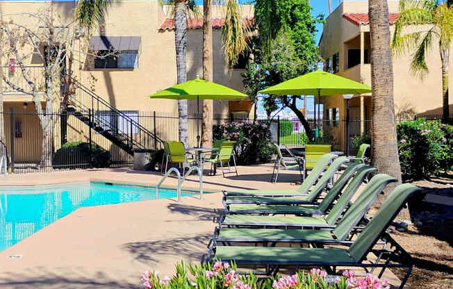 A pool area with green lounge chairs and umbrellas.