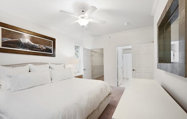 a white bedroom with a large bed and a ceiling fan