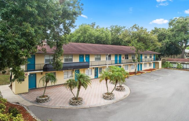 a building with a parking lot and palm trees in front of it