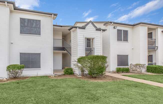 an apartment building with white walls and a grass yard