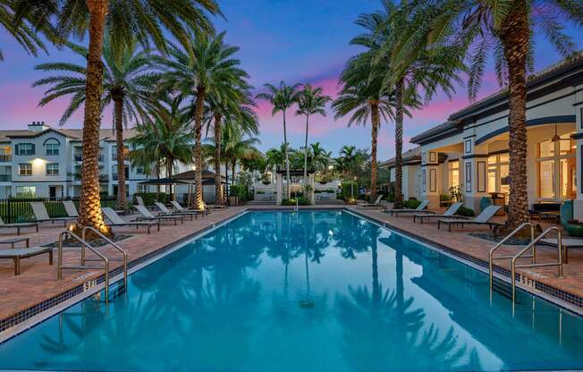 A swimming pool surrounded by palm trees and lounge chairs.