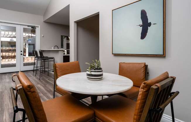 A dining room with a white table and brown chairs.