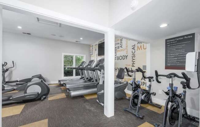 A gym with treadmills, exercise bikes, and a sign that says "Fitness Center Rules".