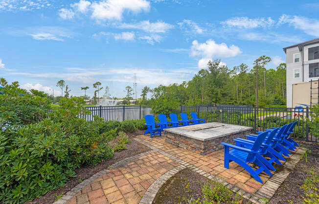 an outdoor patio with blue chairs and a fire pit