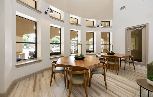 a dining room with a wooden table and chairs and windows