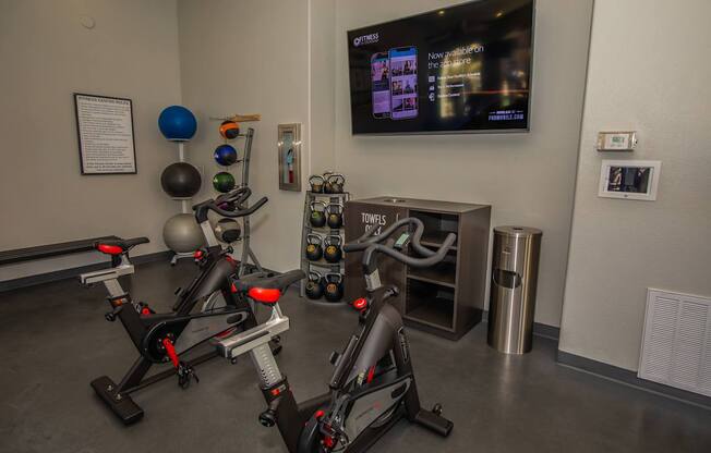 A gym with exercise bikes and a TV screen showing a news program.