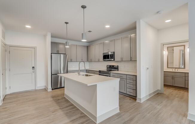 a white kitchen with a large island and stainless steel appliances