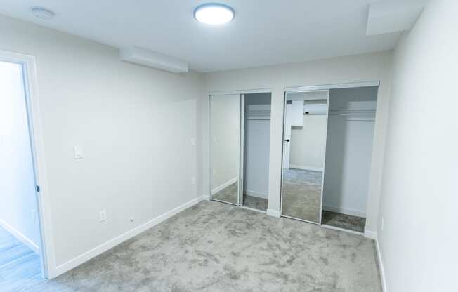an empty room with a carpet and a mirrored closet