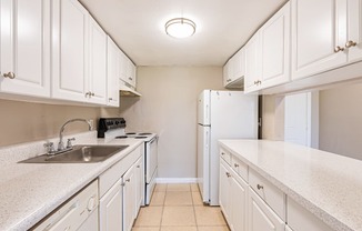 a kitchen with white cabinets and white countertops at Del Rio Apartment