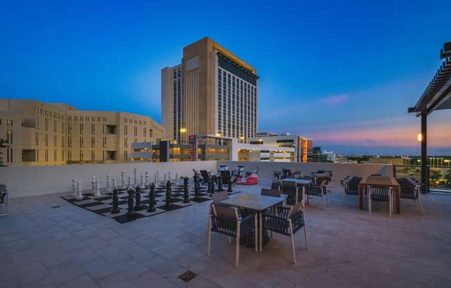 a terrace with tables and chairs and a large building in the background