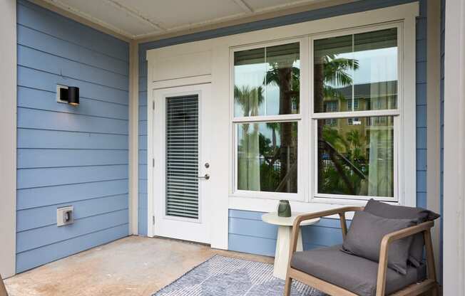 a chair and a table on a porch next to a door