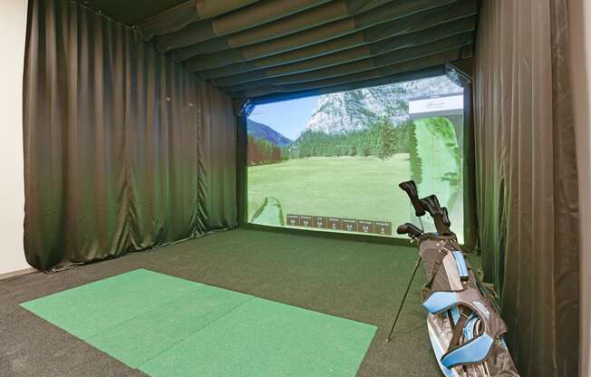 A golf simulator room with a screen showing a golf course.