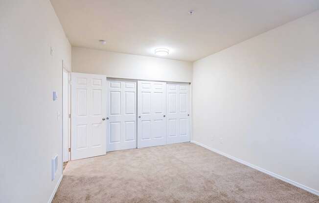 a bedroom with white walls and white doors and carpet