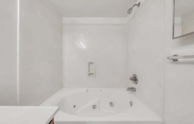 A white bathroom with a tub and a mirror.
