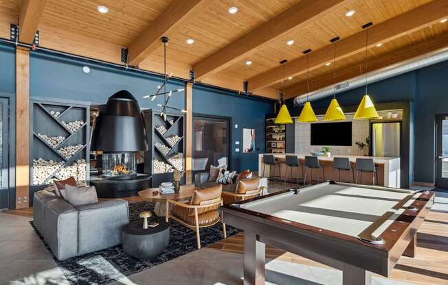 A billiard table is in the middle of a room with a fireplace and a couch.