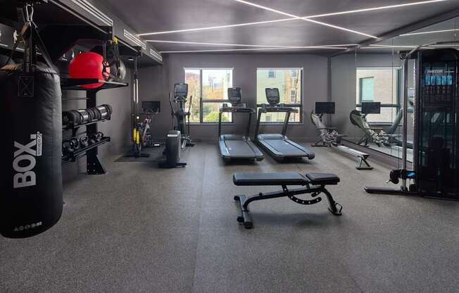 A gym with a punching bag and a bench.