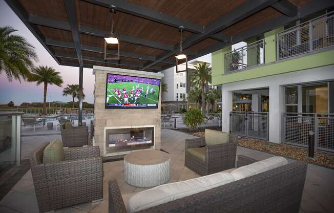 Outdoor TV and fireplace lounge poolside at The Residences at The Green in Lakewood Ranch, Florida