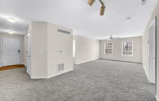 an empty living room with white walls and a ceiling fan