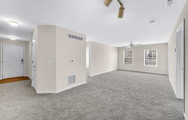an empty living room with white walls and a ceiling fan