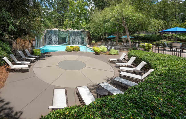 A pool surrounded by a circular patio with lounge chairs.