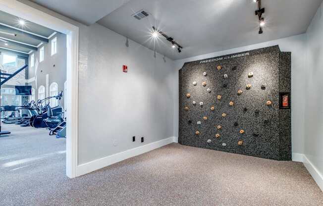 A room with a climbing wall and a gym in the background.
