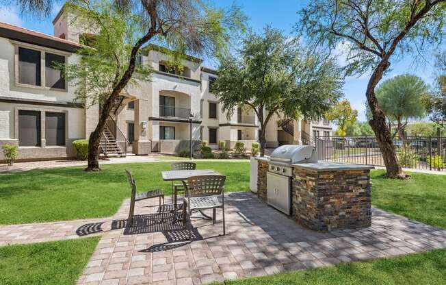 a patio with a grill and a table and chairs