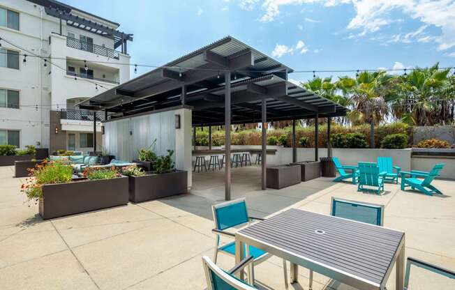 A patio area with a table and chairs under a roof.