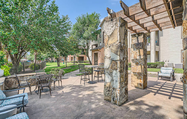 A patio with a table and chairs under a wooden pergola.