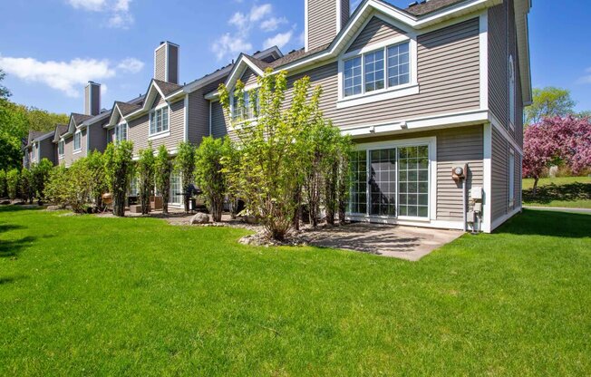 the front of a house with a lawn and trees