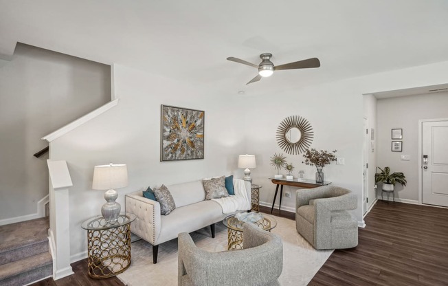 a living room with couches and chairs and a ceiling fan